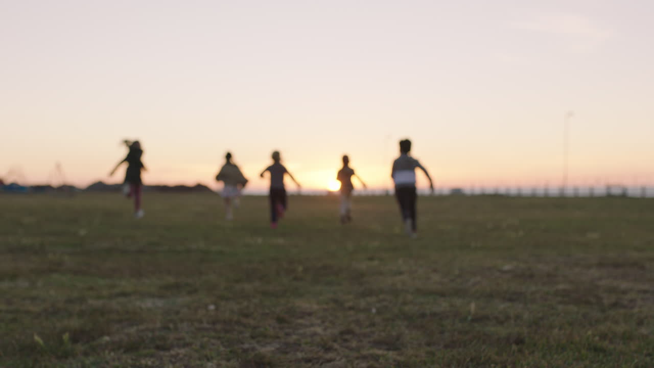 group of happy children portrait running playing in grass field at sunset enjoying fun games together
