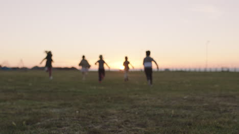 group-of-happy-children-portrait-running-playing-in-grass-field-at-sunset-enjoying-fun-games-together