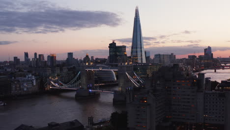 Evening-aerial-view-of-illuminated-Tower-Bridge-across-Thames-river.-Futuristic-The-Shard-skyscraper-in-background.-London,-UK