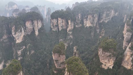 a sweeping aerial drone shot capturing the extensive rock formations and dense green valleys of zhangjiajie, china, showcasing the iconic landscape’s scale and natural beauty