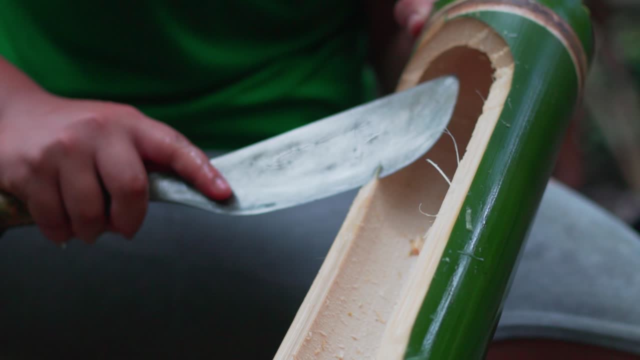 Local camper chopping the bamboo shoot to remove splinters to cook food