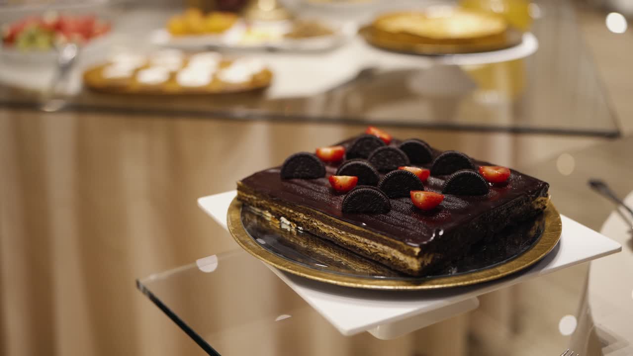 Chokoladekage toppet med småkager og jordbær serveret på tallerken ved dessertbordet.