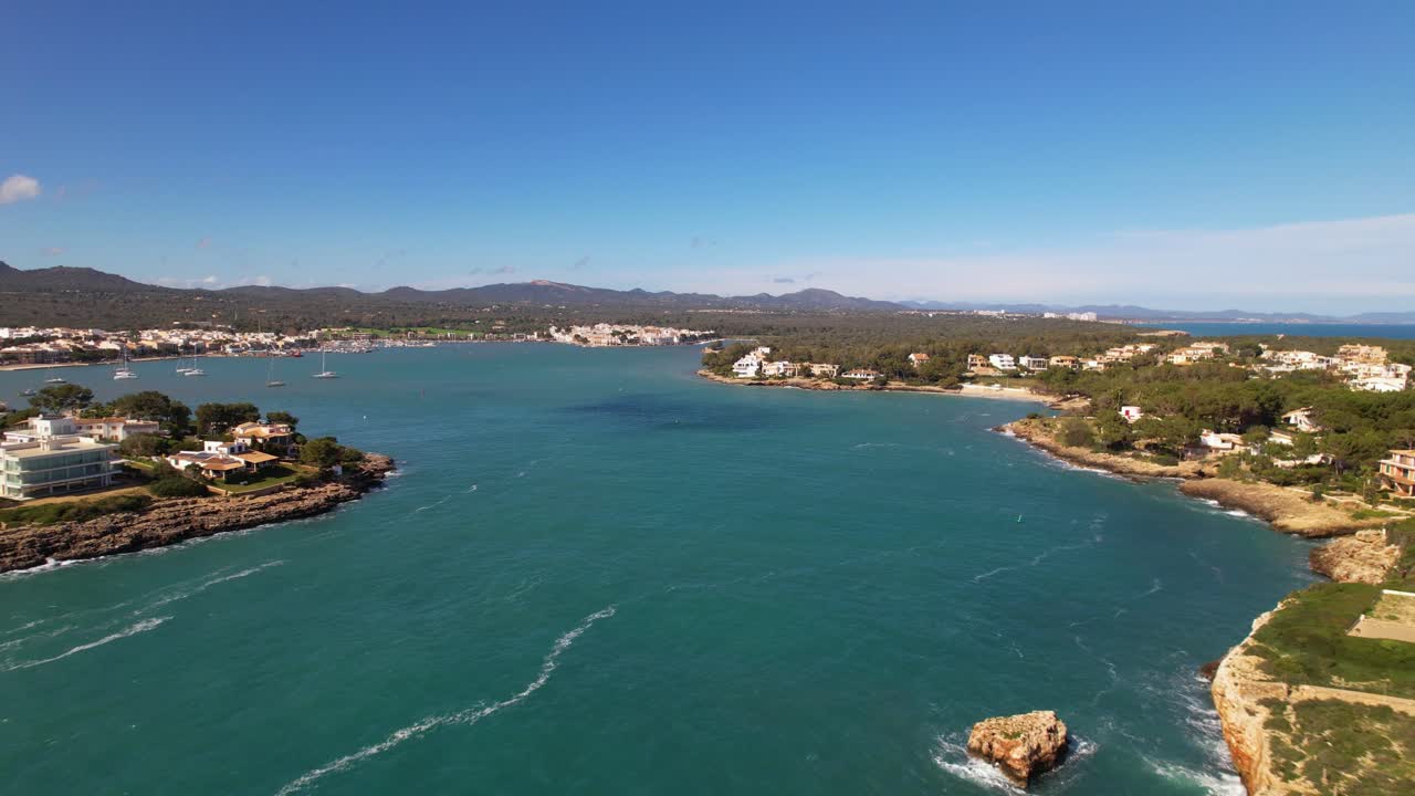 Drone footage of a black and white striped lighthouse on a cliff near Portocolom