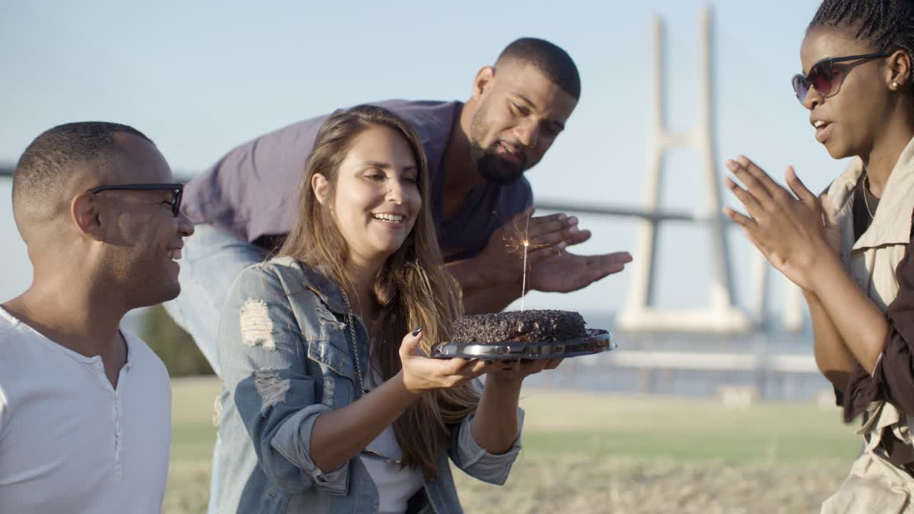 Femme souriante aux cheveux longs tenant un gâteau avec une bougie magique