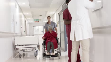 diverse female nurse walking with senior patient in wheelchair in slow motion, unaltered