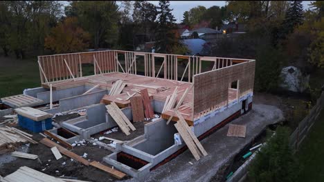 drone shot of housing construction site in the evening with wood framing and concrete basement in progress