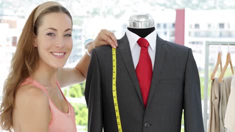 diseñador de moda sonriente midiendo el traje en el maniquí