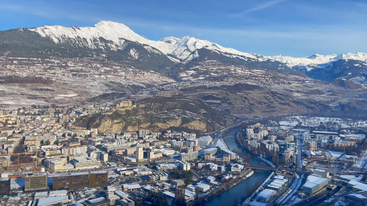 Helikopterstart-Schwenkaufnahme der Schweizer Stadt Sion in den schneebedeckten Alpen an einem sonnigen Wintertag