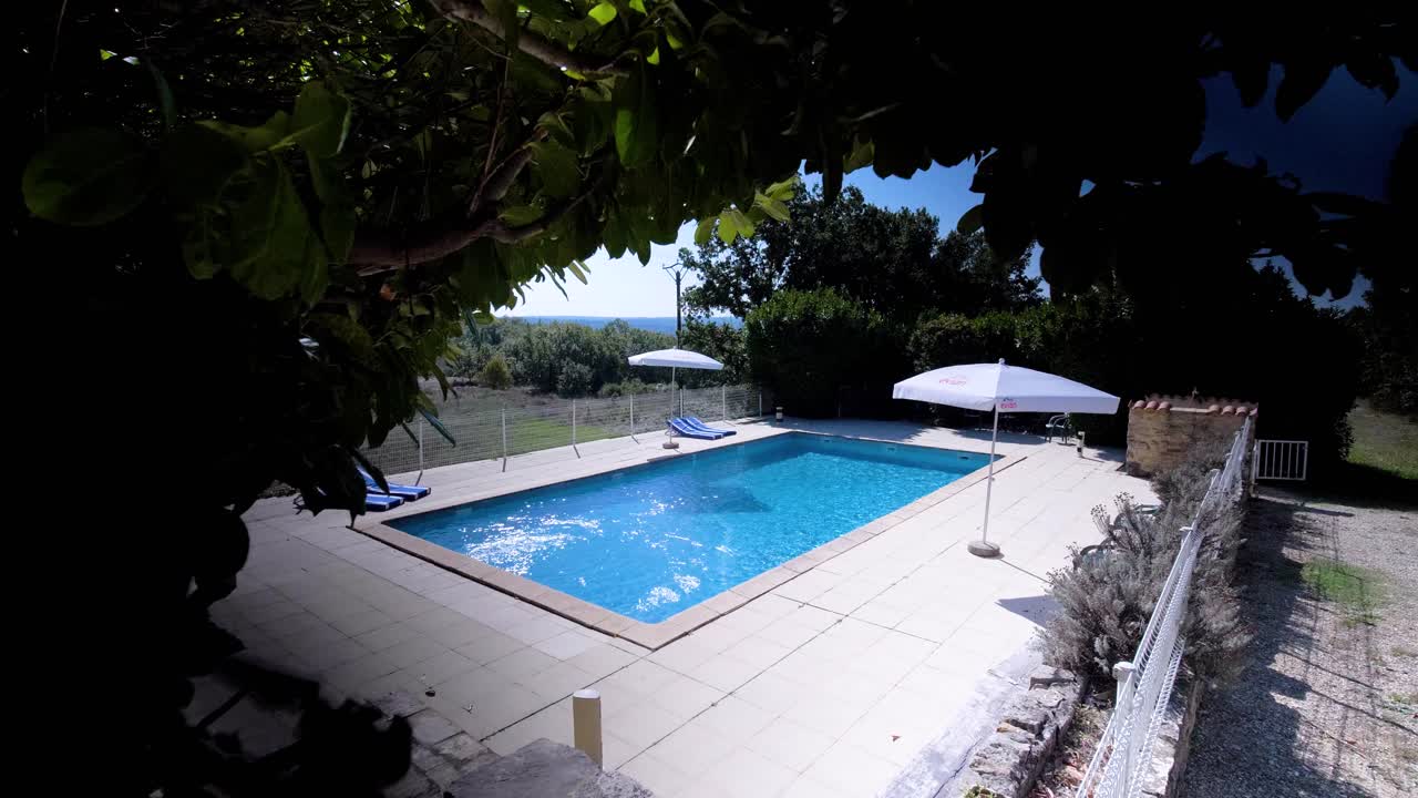 Langsomt afslørende optagelse af en privat pool omgivet af træer i fuldt flor