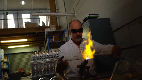 Front-view-of-mature-male-worker-creating-glass-in-glass-factory-4k