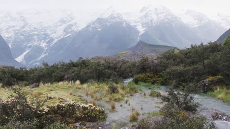 Campo-Cubierto-De-Agua-De-Inundación-Debido-Al-Derretimiento-De-La-Nieve-Primaveral-Con-Montañas-Nevadas-En-El-Fondo