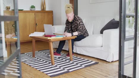 hombre albino afroamericano con rastas trabajando y usando una computadora portátil