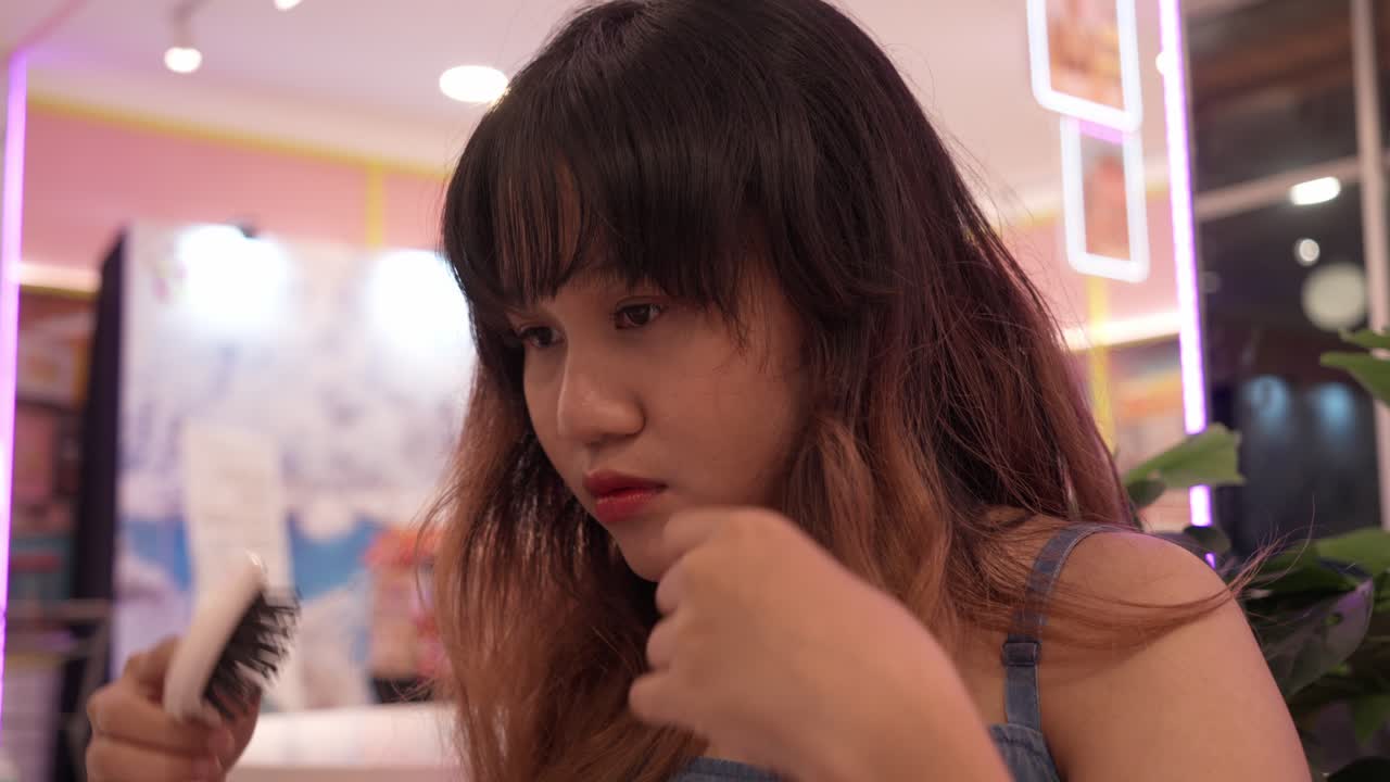 Indonesian girl fixing her hair in front of the mirror, adjusting her bangs