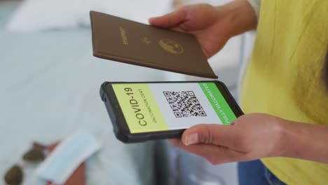 de manos mujer asiática con pasaporte y teléfono inteligente con pasaporte covid en la pantalla para viajar