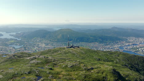 aerial footage circling ulriken on a sunny summer day, capturing panoramic mountain, fjord and city views over bergen