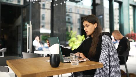 mujer joven trabajando en una computadora portátil en un café