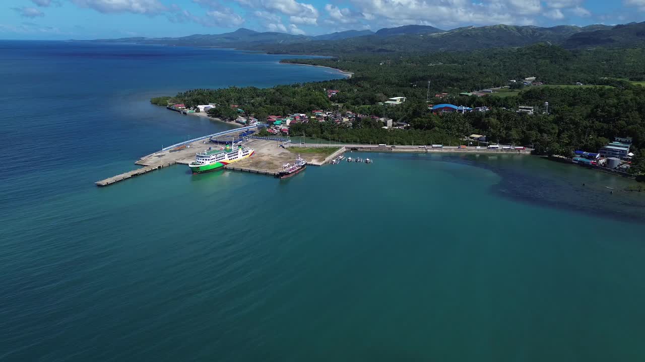 Vista aerea con drone del porto di Odiongan a Romblon, Filippine, che mostra un grande traghetto passeggeri attraccato al porto con la città costiera e la costa visibili sotto un cielo azzurro limpido in una giornata di sole