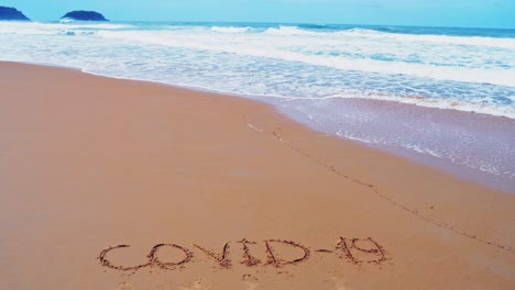 Text-COVID-19-on-the-sea-beach-and-splashing-waves-on-the-sand-during-the-lockdown-time-with-the-slow-motion-wave-in-nature-concept