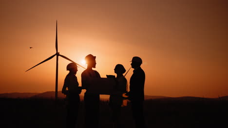ingenieros discutiendo planes de parques eólicos al atardecer