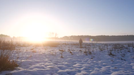 día soleado de invierno y el hombre caminando sobre la nieve