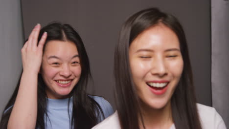 Two-Female-Friends-In-Photo-Booth-Having-Fun-Posing-For-Portrait-And-Pulling-Faces