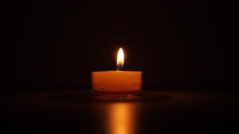 Candle-with-its-orange-flame-in-the-dark