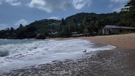 Waves-reaching-the-sandy-shore-on-a-populated-beach-on-the-island-of-Koh-Samui,-Thailand