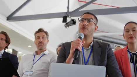 miembro de la audiencia masculina en una conferencia de negocios haciendo una pregunta