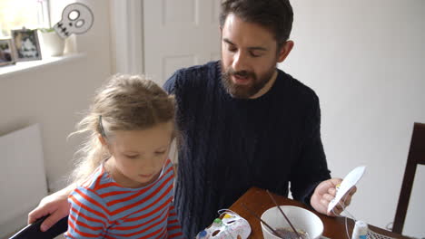 padre e hija haciendo máscaras de halloween en casa juntos