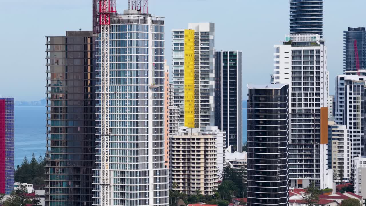High-rise buildings and skyscrapers line a coastal city with ocean in the background, captured in daylight with smooth lateral drone camera movement