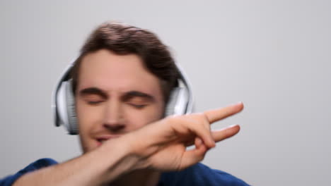 hombre escuchando música en auriculares. tipo bailando en auriculares en un fondo claro