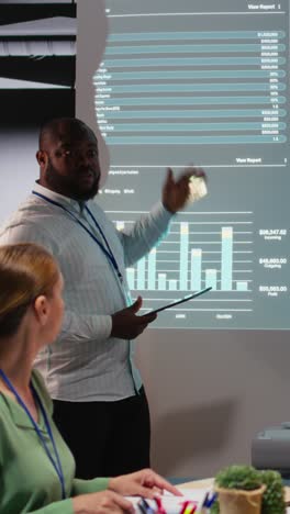 vertical video multiethnic staff members examining data insights to evaluate business activity