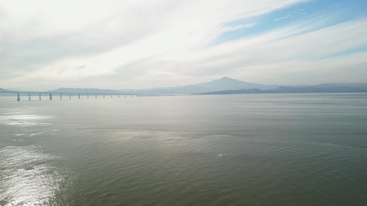 Panning drone capture of the Richmond–San Rafael Bridge with the bay and Point Molate Beach below.
