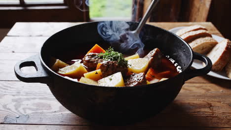 serving hot beef and potato stew from a cast-iron pot