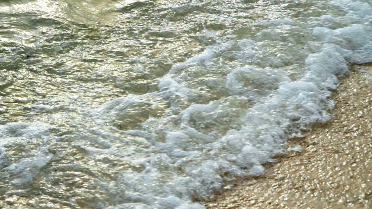 해가 지는 동안 열대 지방의  ⁇  모래 해변의 해안에 도달하는 파도와 함께 아름다운 해변