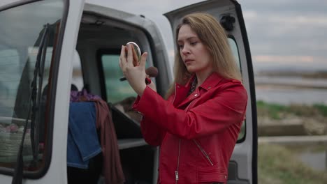 woman applying makeup in a van