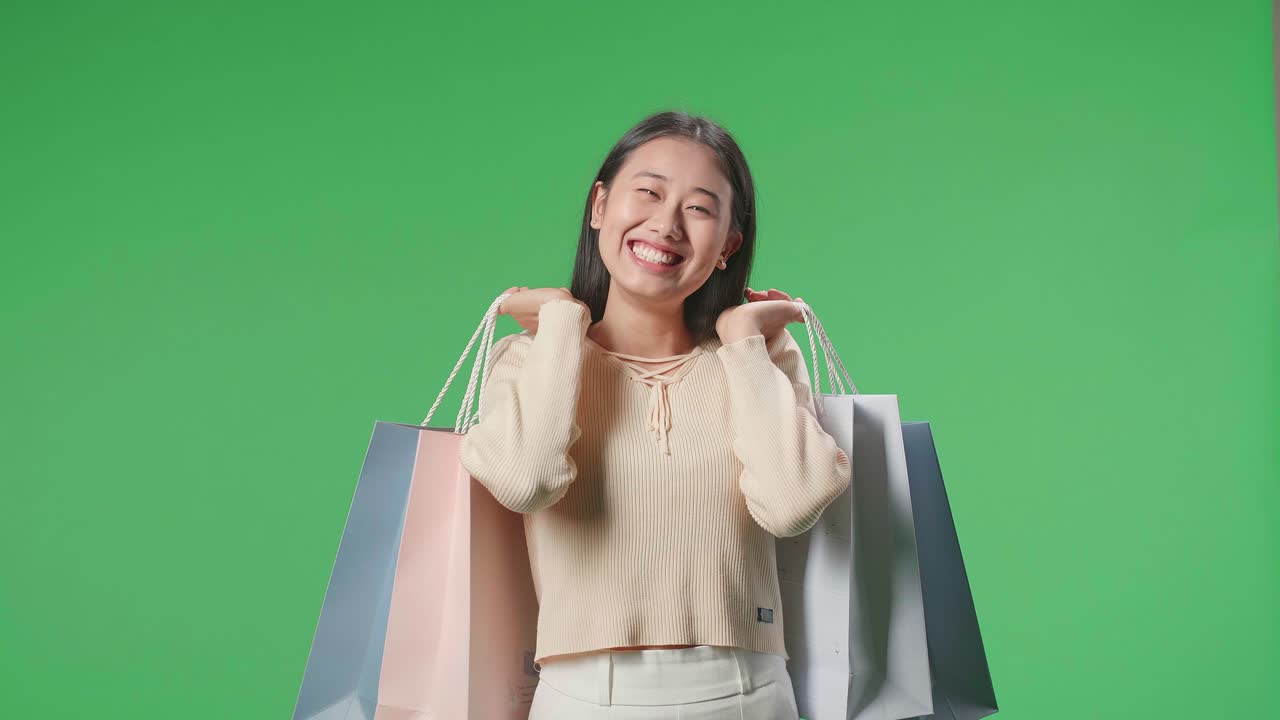 An Asian Shopping Woman Holding Shopping Bags Up Being Happy And Smiling To Camera While Standing In Front Of Green Screen