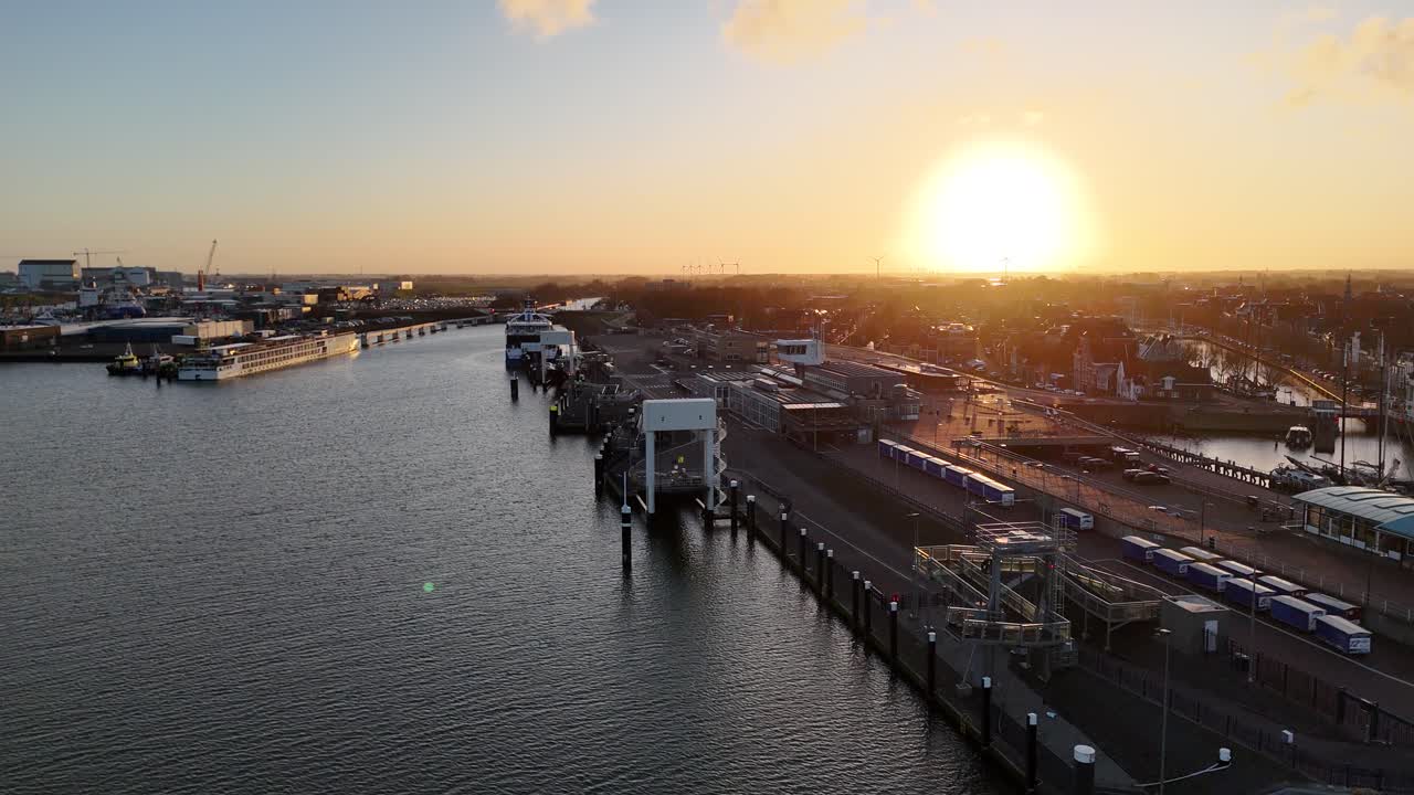 Drone tracks away with the sun behind and the harbor spread across the frame