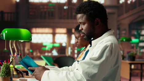 african american medical student reads under green lamps in a library