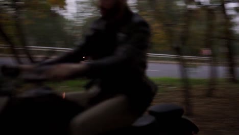 front view of a guy rides a motorcycle cross country between trees