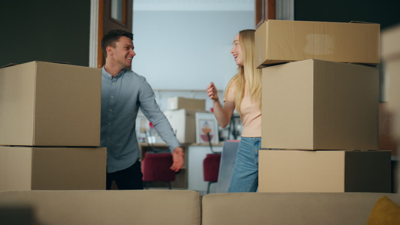 una pareja de propietarios felices abrazándose al entrar en una casa nueva con cajas de cartón.
