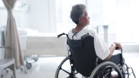 african american female senior patient in wheelchair in hospital room, slow motion