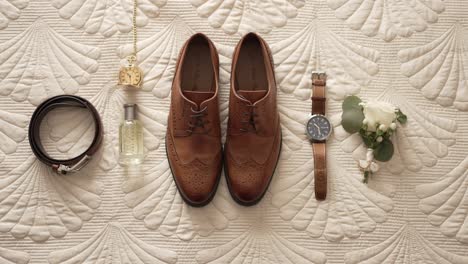 flat lay of groom wedding items with shoes watch belt and boutonniere