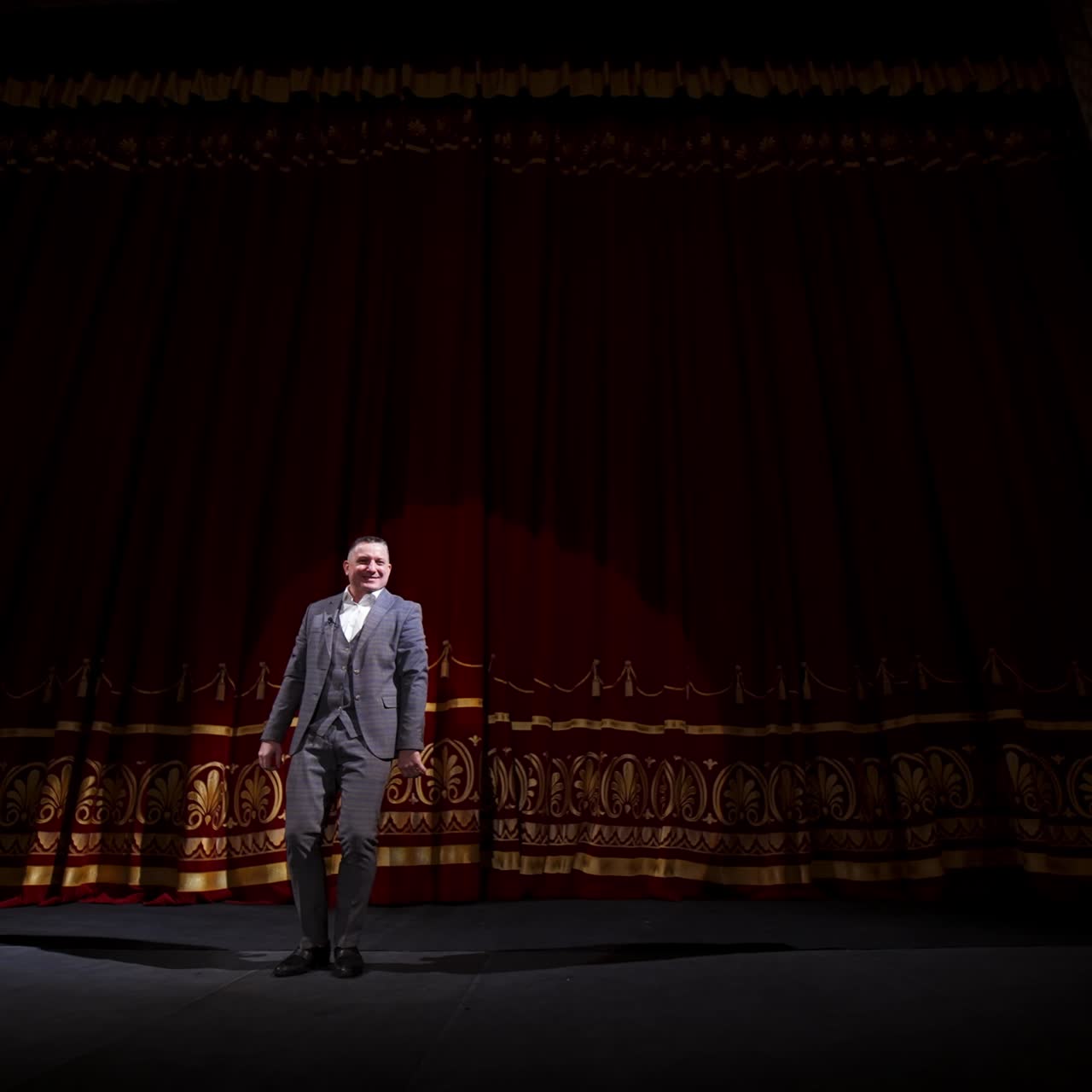 Middle age male entertainer, presenter or actor on stage. Public speaker gives performance. Man in theater