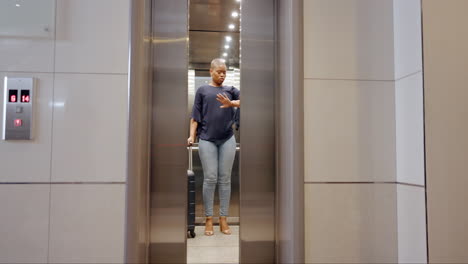 maleta, viaje y mujer negra en el ascensor
