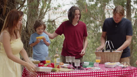 happy family putting food from basket on table during a picnic in the forest