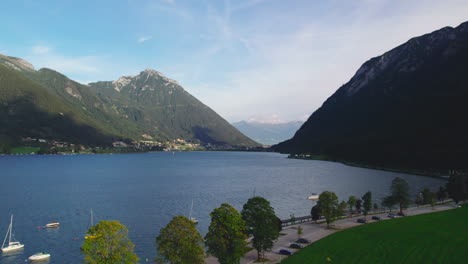 flying over boat sailing on achensee lake, pertisau, with austrian mountain range landscape