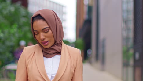 close up of modern muslim businesswoman wearing hijab walking on way to work in office looking at mobile phone 1