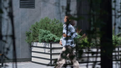 smiling woman holding coffee cup walking around city. corporate people concept.