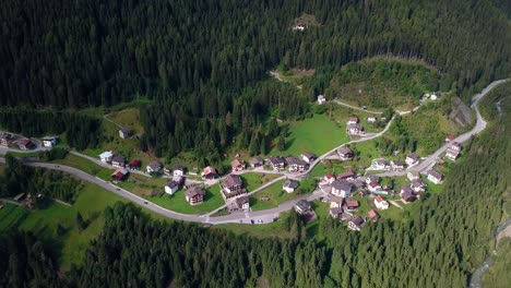 Pueblo-De-Montaña-En-El-área-De-Dolomita-En-El-Norte-De-Italia-Con-Caminos-Que-Pasan-A-Través-De-Edificios-Y-Casas,-Automóviles-Que-Pasan,-Vista-Aérea-De-Drones